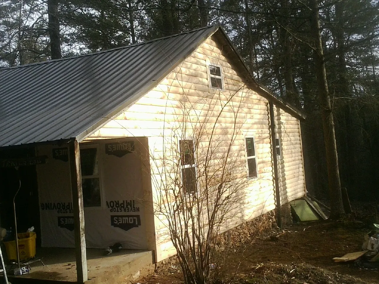 Log siding gable end under a dark metal roof edge in Erin