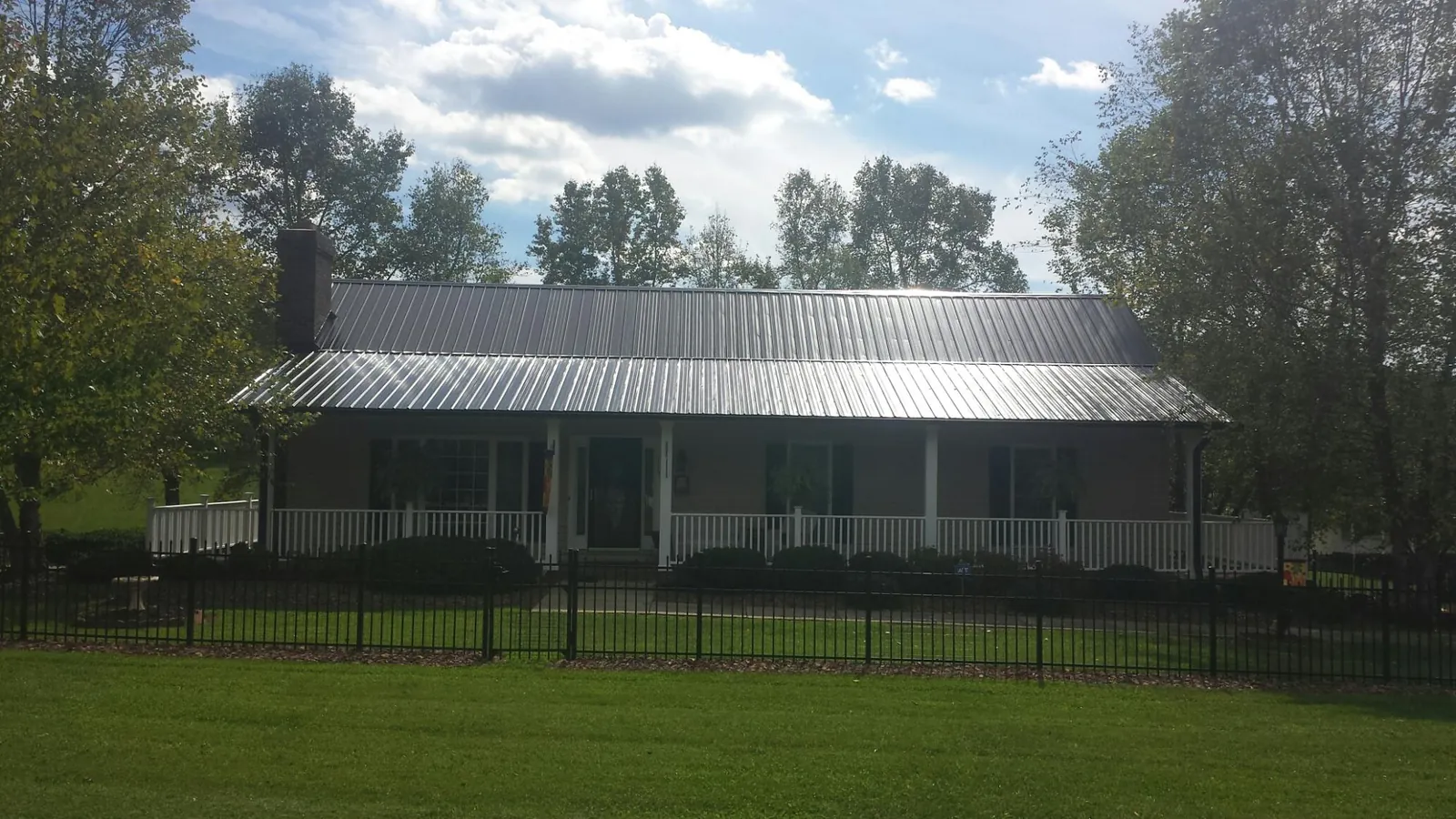 Gray metal roof on a brick ranch with a full width front porch — Gutter Guard Installation work by our crew in Erin